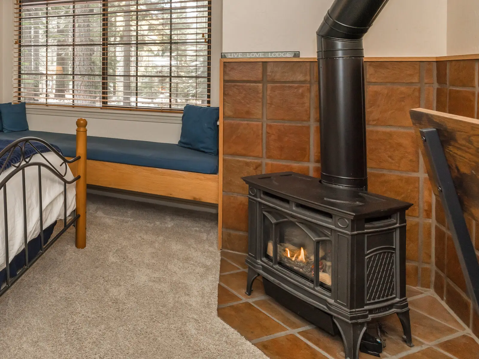 The gas fireplace stove in a Deluxe Suite, flame lit, beside the window seat